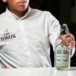 A bartender in Los Toros Restaurant displaying a bottle of Tequila 30-30, Reserva Especial.